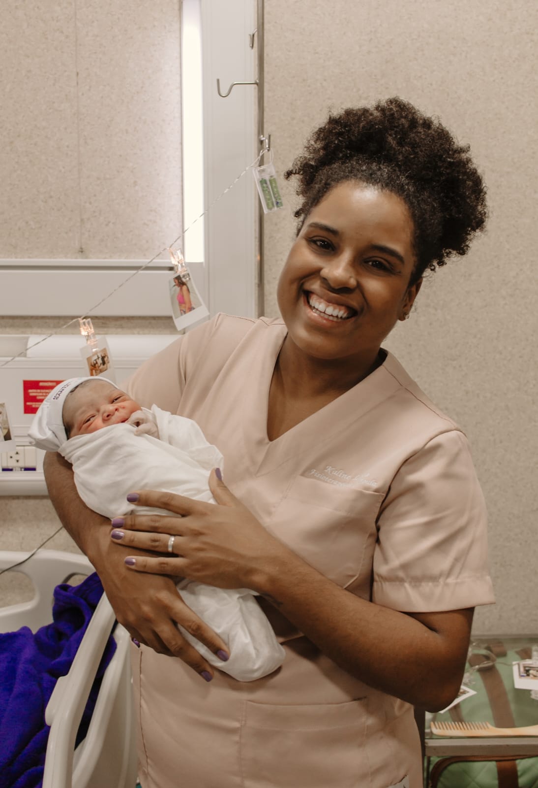 Doula sorrindo segurando recém-nascido enrolado