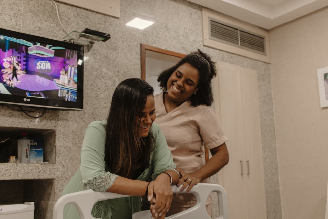 Doula apoiando gestante que sorri no leito hospitalar